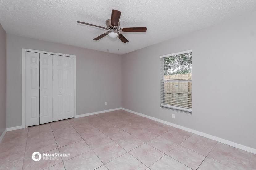 the living room of an empty home with a ceiling fan