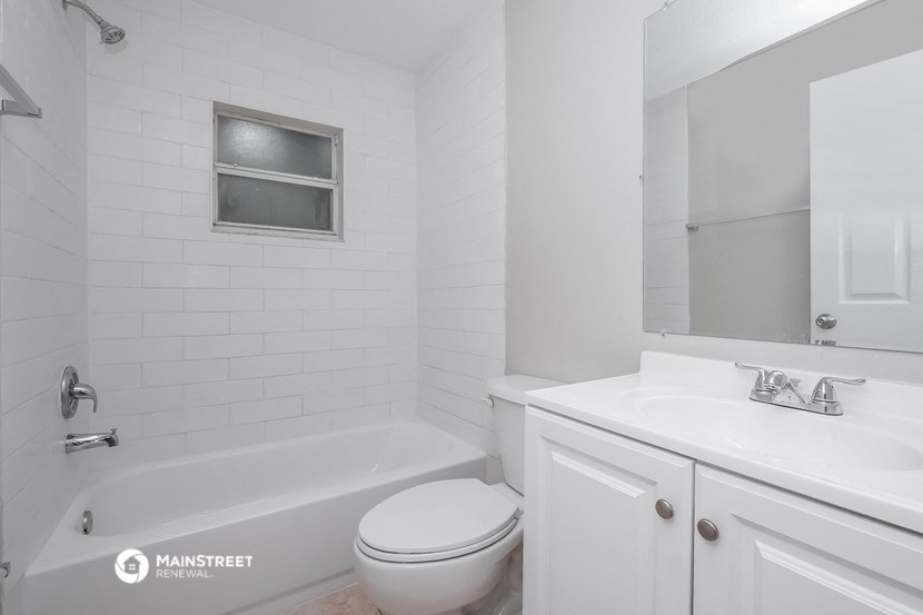 a white bathroom with a tub and a sink and a toilet