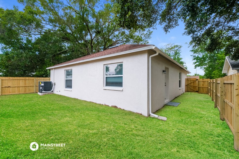 a small white house with a yard and a wooden fence