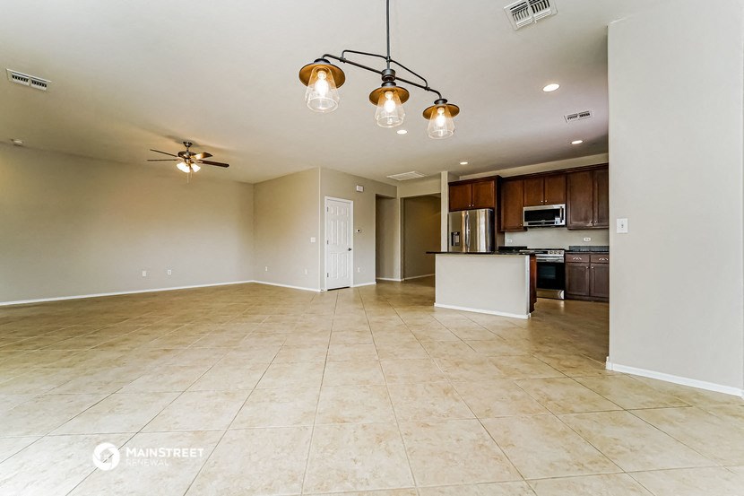 an empty living room with a kitchen in the background