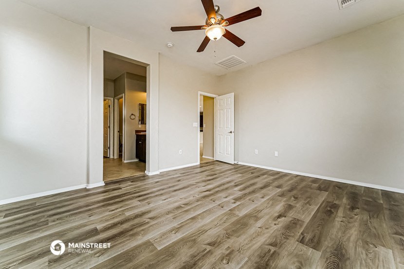 an empty living room with wood flooring and a ceiling fan