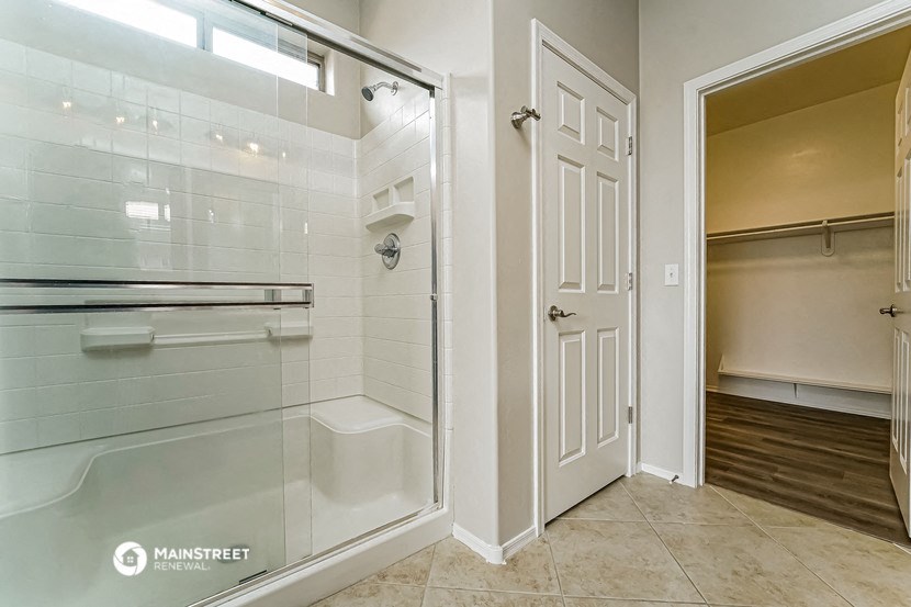 a bathroom with a glass shower and a door to a closet