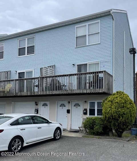 A white car is parked in front of a blue building.