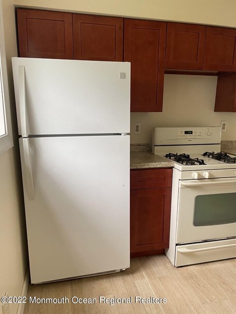 A white refrigerator stands next to a stove in a kitchen.