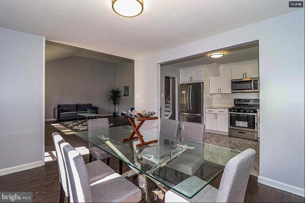 A dining room with a glass table and grey chairs.