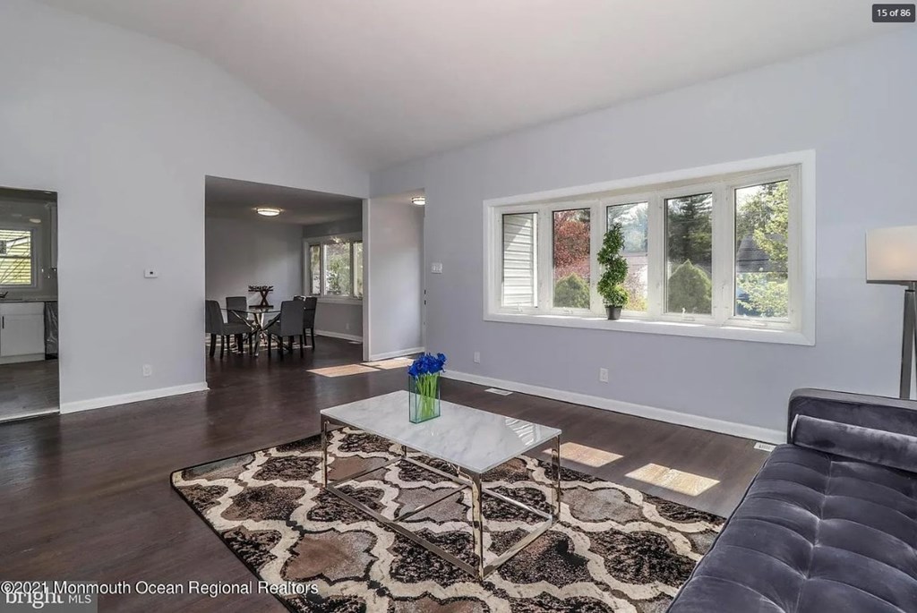A living room with a black couch and a patterned rug.