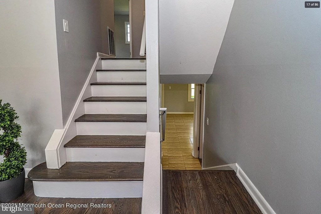 A staircase with a wooden handrail and steps leading to a doorway.