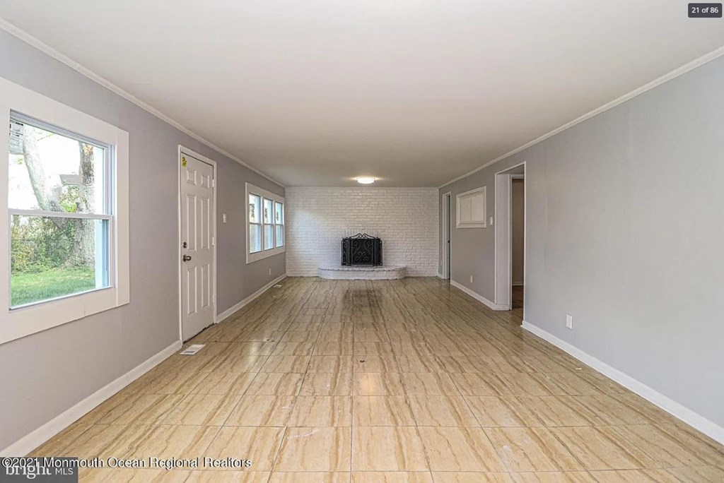 A spacious room with wooden flooring and white walls.
