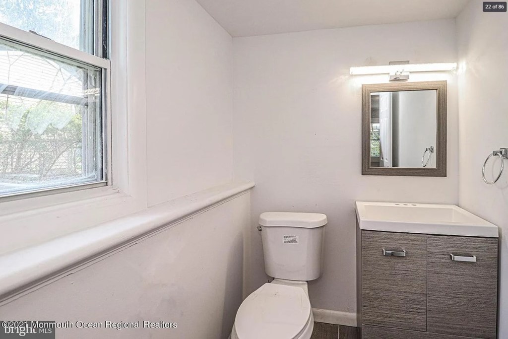 A bathroom with a toilet, sink, and mirror.