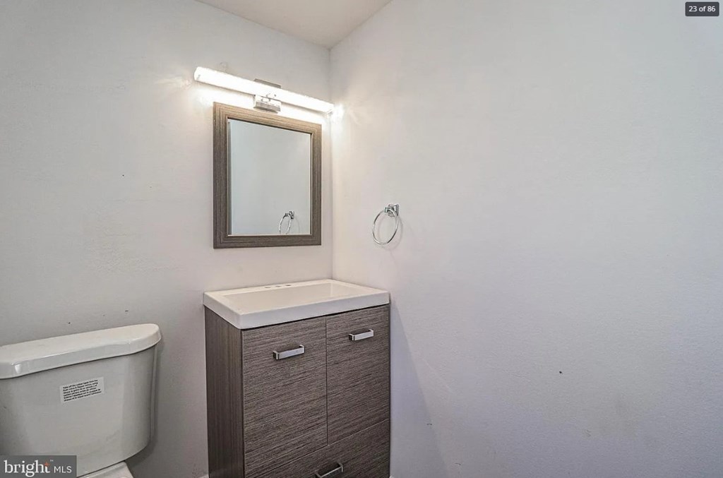 A white toilet sits next to a cabinet with a mirror above it.