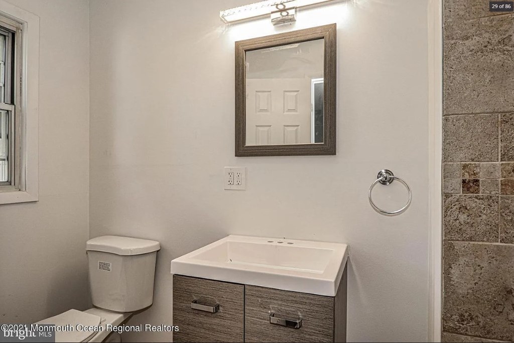 A bathroom with a toilet, sink, and mirror.