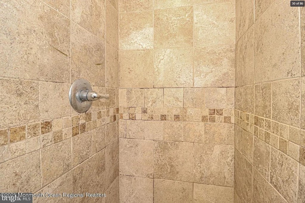 A shower with a tiled wall and floor.
