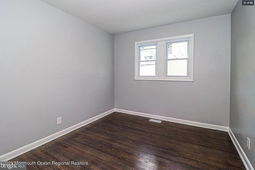 A room with a window and wooden flooring.