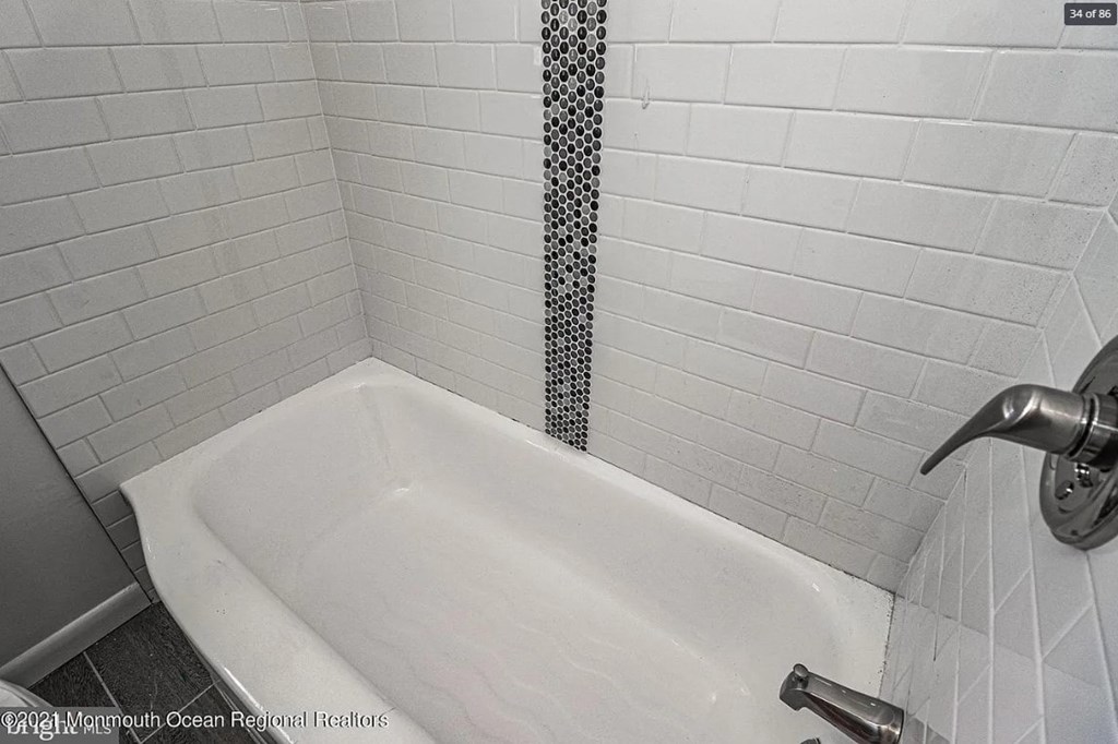 A white bathtub in a bathroom with a shower head.