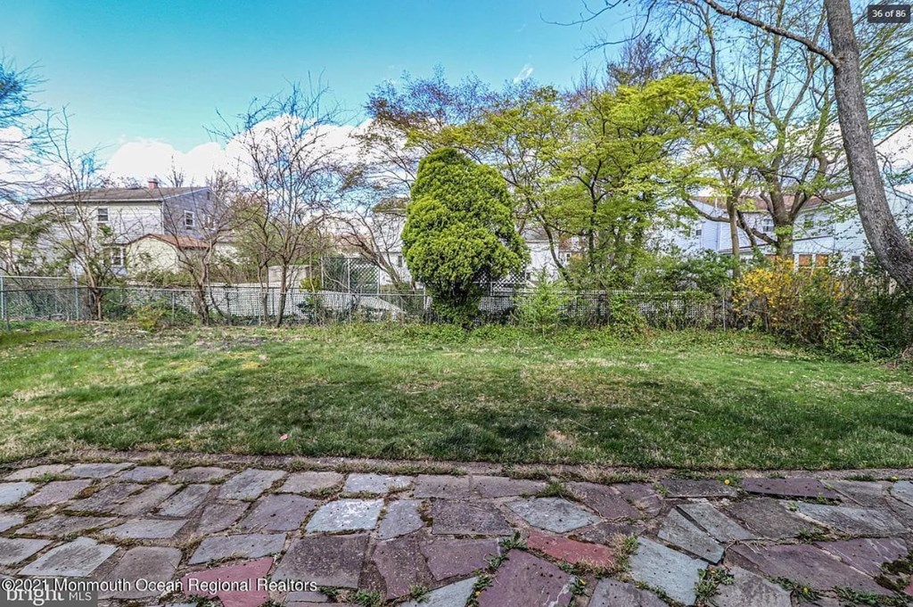 A backyard with a stone pathway and a green lawn.