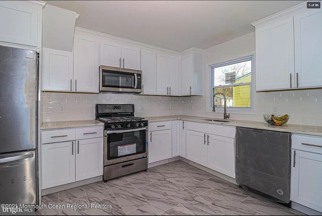 A kitchen with white cabinets and a black stove top oven.
