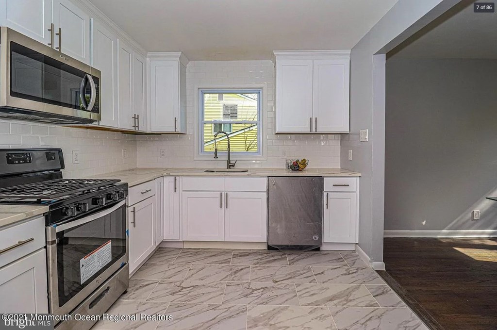 A kitchen with white cabinets and a tiled floor.