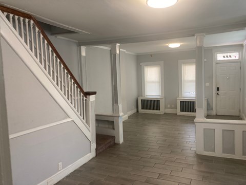 A spacious room with a staircase and radiators.