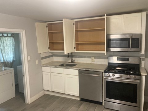 A kitchen with white cabinets and a stainless steel oven.