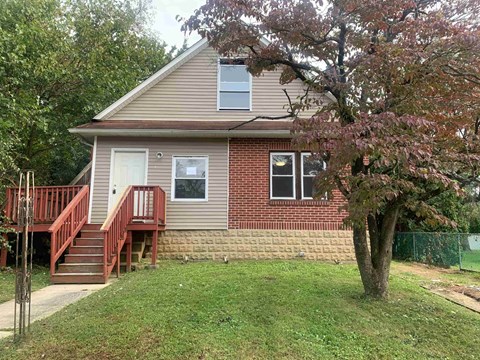A house with a red staircase and a tree in front.