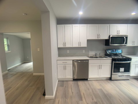 A kitchen with white cabinets and a wooden floor.