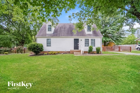 a small white house with a yard and a wooden fence
