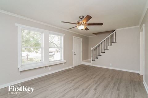 an empty living room with a ceiling fan and a window