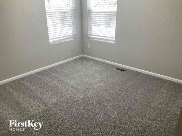 an empty room with a carpet floor and two windows