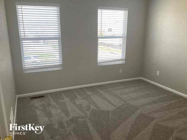 an empty room with two windows and a carpeted floor
