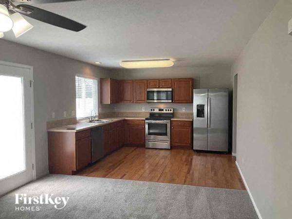 an empty kitchen with stainless steel appliances and wood floors