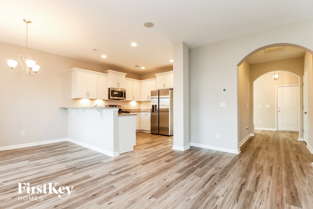a kitchen and living room with wood floors and white cabinets