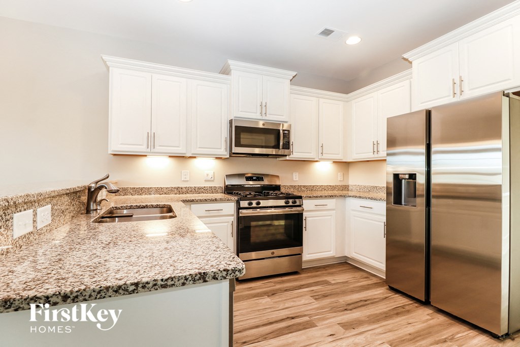 a kitchen with white cabinets and stainless steel appliances and granite counter tops