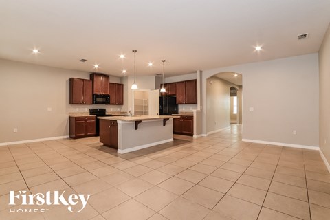 an open kitchen and living room with tile flooring and wooden cabinets