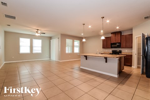 an open kitchen and living room with tile flooring