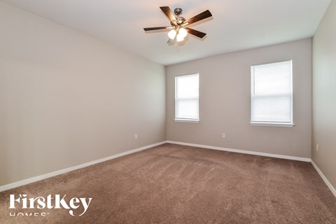 the upstairs bedroom with carpet and ceiling fan and two windows