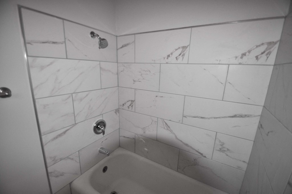 a white tiled bathroom with a tub and a sink