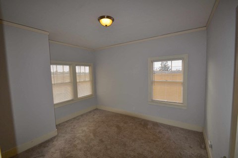 a room with a carpet and two windows