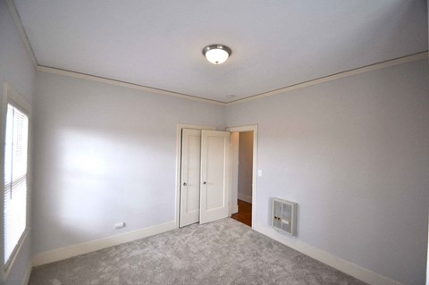 a bedroom with white walls and a door to a closet