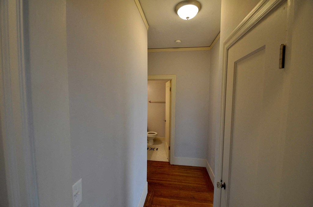 a hallway with a door to a bathroom and a toilet