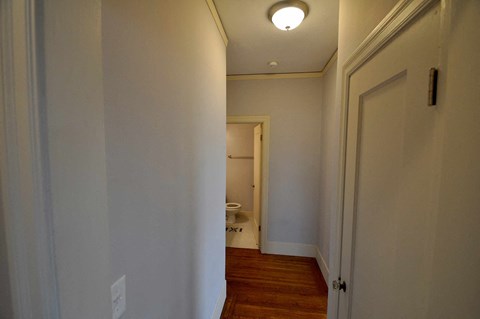 a hallway with a door to a bathroom and a toilet
