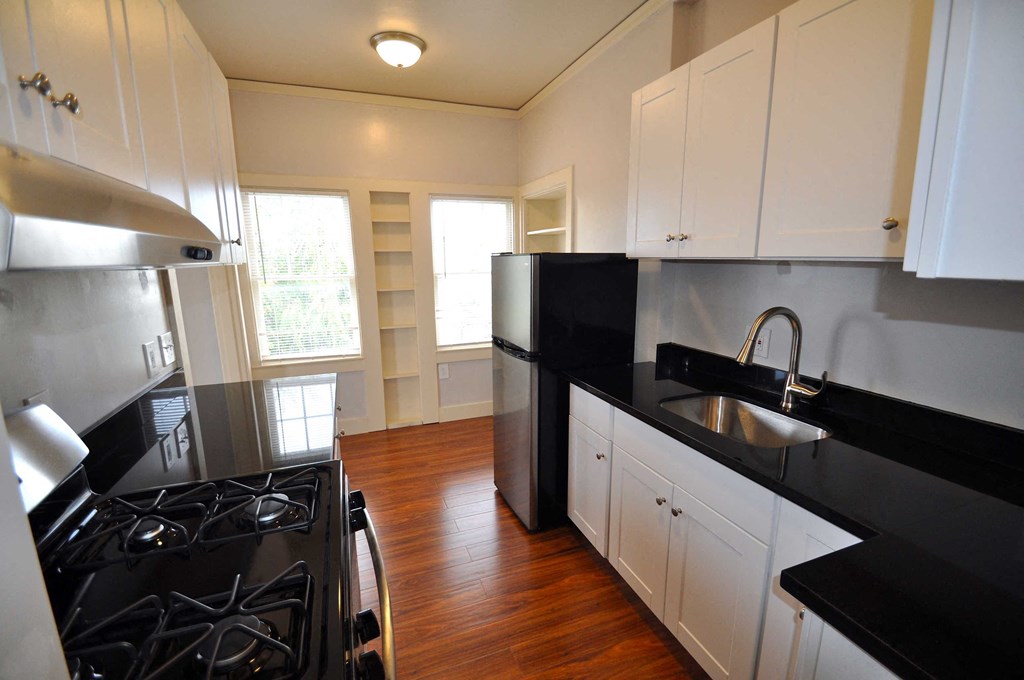 a kitchen with black counter tops and a stove and a sink