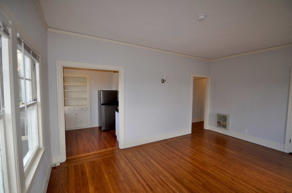 a living room with a hard wood floor and a door to a bedroom