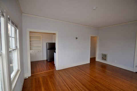 a living room with a hard wood floor and a door to a bedroom