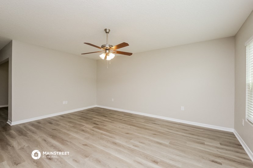 the spacious living room with hardwood floors and a ceiling fan