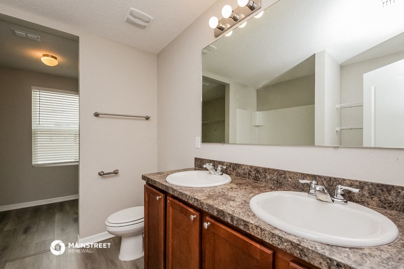 a bathroom with two sinks and a toilet and a large mirror