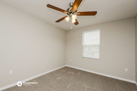 the spacious living room with ceiling fan and carpet