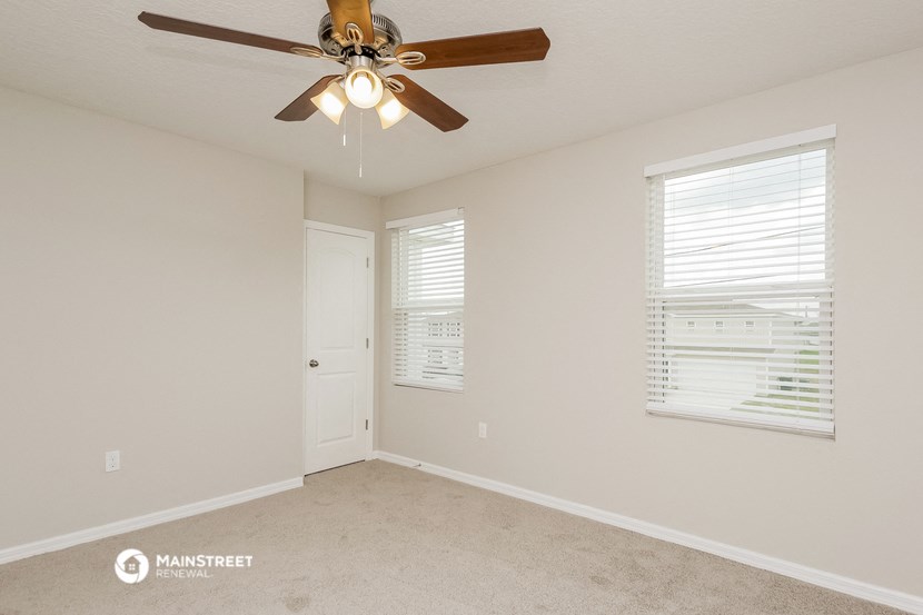 the spacious living room with ceiling fan and window