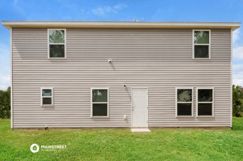the front of a small gray house with a white door