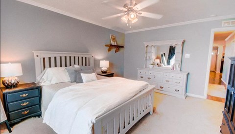 a bedroom with a white bed and a ceiling fan