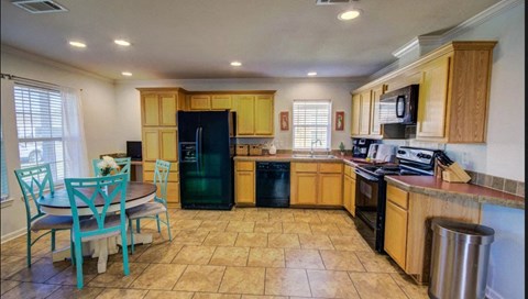 a kitchen with a dining table and a black refrigerator